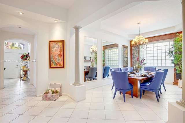 dining space with light tile patterned floors, a chandelier, and ornate columns