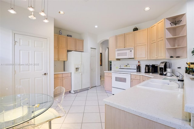 kitchen featuring white appliances, decorative light fixtures, sink, and light brown cabinets