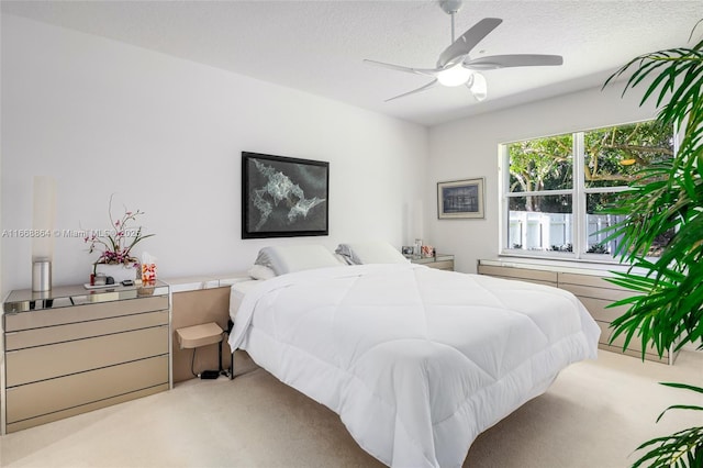 bedroom featuring light carpet, ceiling fan, and a textured ceiling