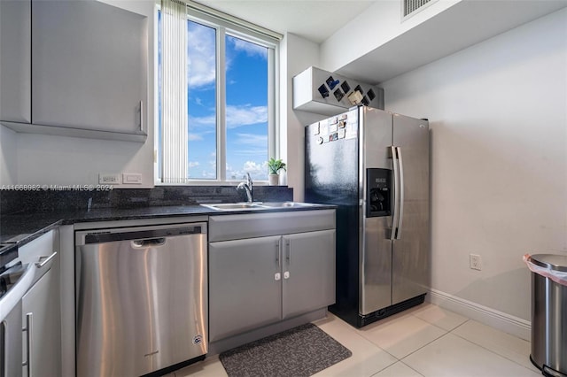 kitchen featuring light tile patterned flooring, appliances with stainless steel finishes, sink, and dark stone counters