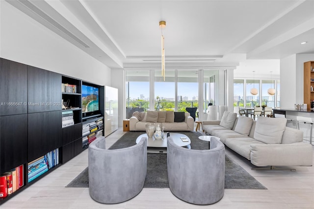 living room featuring light wood-type flooring, a wall of windows, and a wealth of natural light