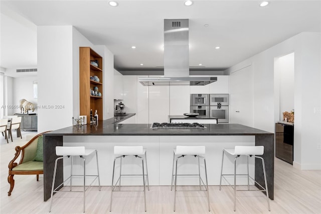 kitchen featuring white cabinets, kitchen peninsula, island exhaust hood, light wood-type flooring, and beverage cooler