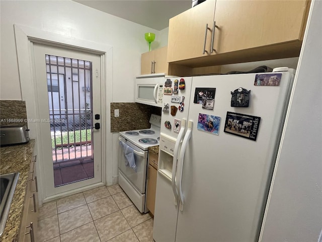 kitchen with dark stone countertops, white appliances, and light tile patterned floors