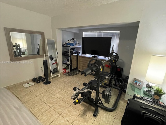 workout area with a textured ceiling and light tile patterned floors