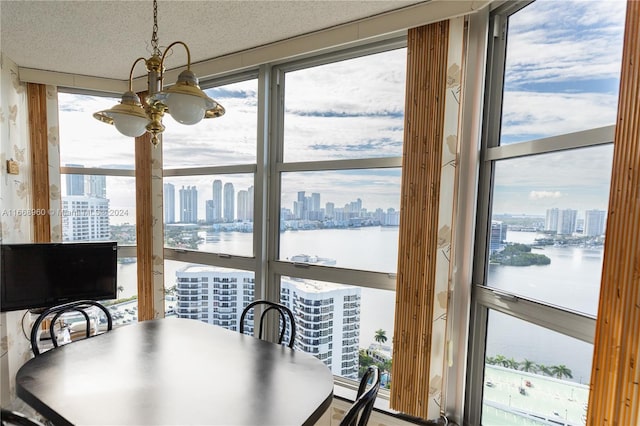 dining area featuring a textured ceiling, an inviting chandelier, floor to ceiling windows, and a water view