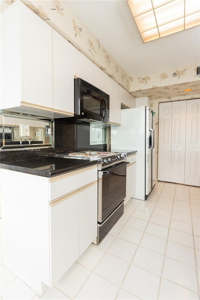 kitchen featuring a textured ceiling, black appliances, white cabinetry, and light tile patterned floors