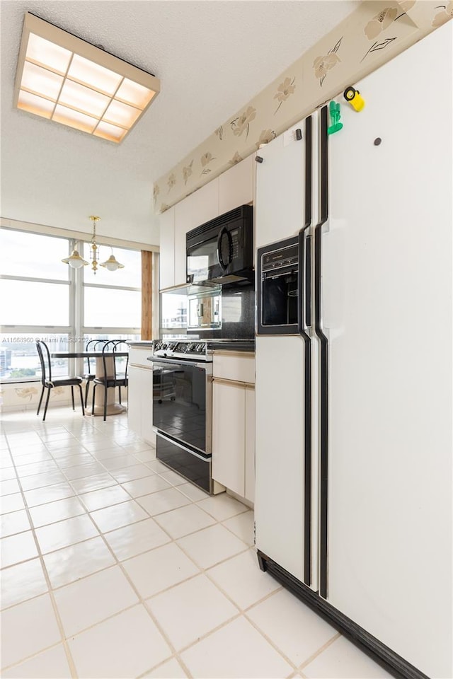 kitchen featuring black appliances, white cabinetry, light tile patterned floors, and a chandelier