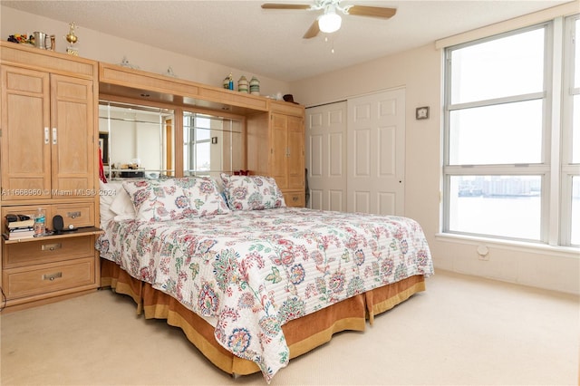 carpeted bedroom with ceiling fan and a closet