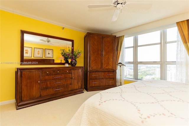 carpeted bedroom with ornamental molding and ceiling fan