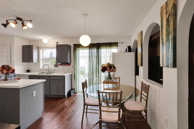 dining space featuring a textured ceiling, sink, and dark wood-type flooring