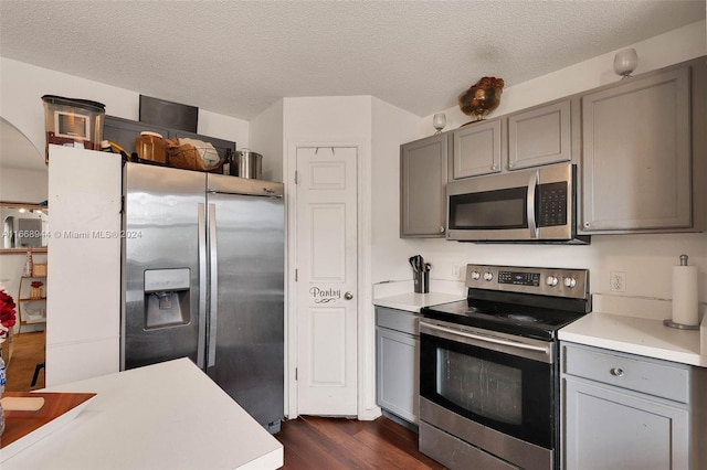 kitchen featuring gray cabinetry, stainless steel appliances, a textured ceiling, and dark hardwood / wood-style floors