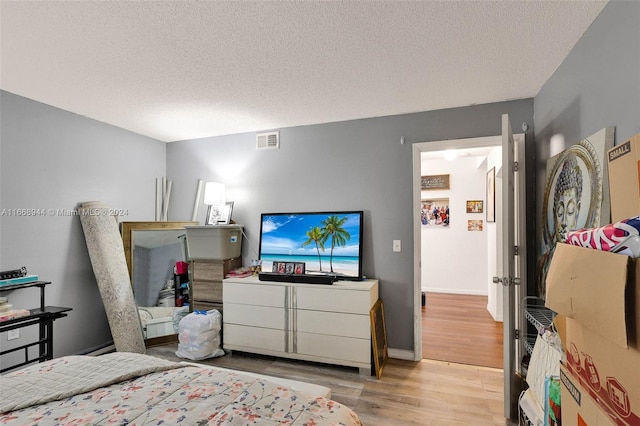 bedroom featuring a textured ceiling and light hardwood / wood-style flooring