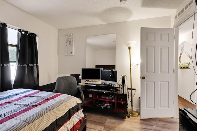 bedroom featuring a textured ceiling, wood-type flooring, and lofted ceiling