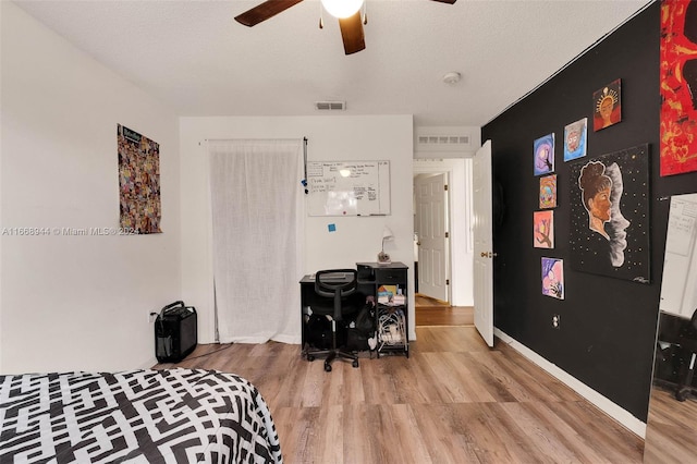 bedroom featuring ceiling fan, hardwood / wood-style flooring, and a textured ceiling