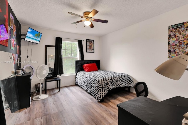 bedroom with a textured ceiling, ceiling fan, and hardwood / wood-style flooring