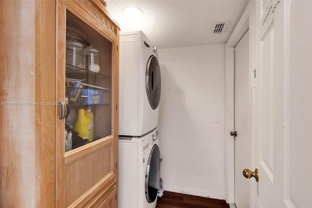 laundry area with stacked washer / dryer, a textured ceiling, and dark hardwood / wood-style floors