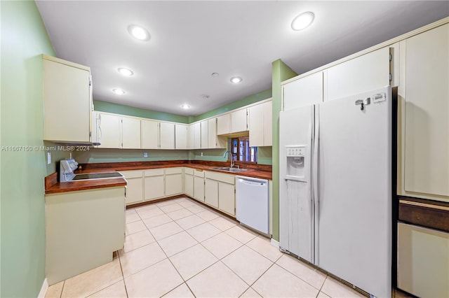 kitchen with white cabinetry, sink, light tile patterned floors, and white appliances