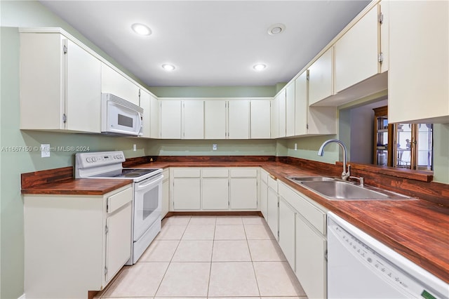 kitchen with sink, light tile patterned flooring, white cabinetry, butcher block countertops, and white appliances