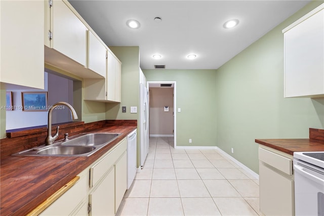 kitchen featuring sink, white cabinets, light tile patterned floors, butcher block countertops, and white appliances