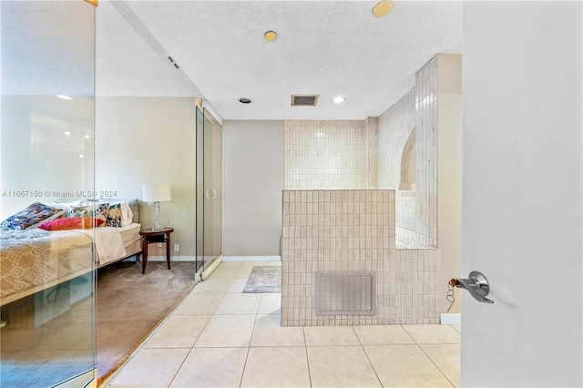 bathroom featuring tile patterned floors, a shower, a textured ceiling, and tile walls