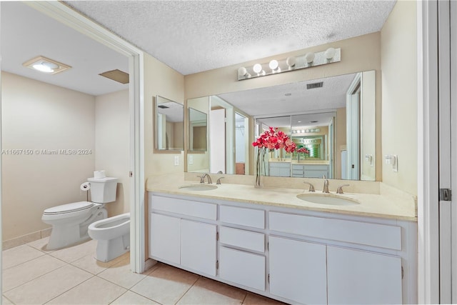 bathroom with vanity, a textured ceiling, a bidet, and toilet