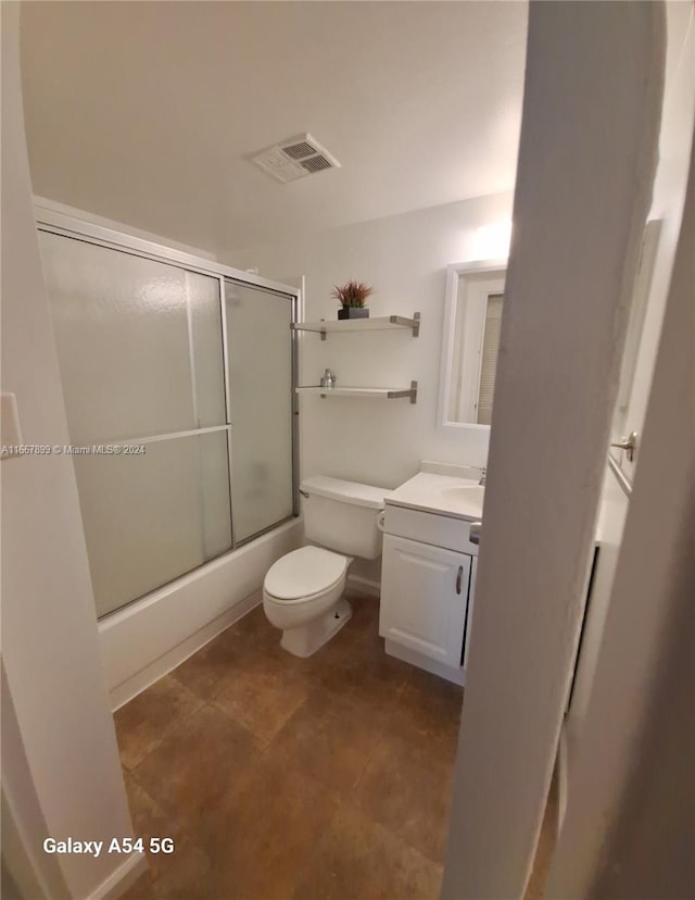 full bathroom with bath / shower combo with glass door, vanity, and toilet