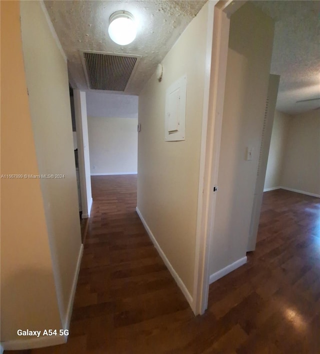 hall featuring electric panel, dark wood-type flooring, and a textured ceiling