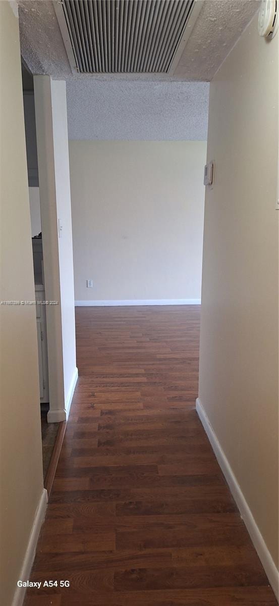 hall featuring a textured ceiling and dark hardwood / wood-style flooring