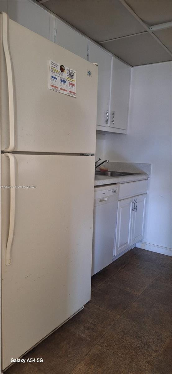 kitchen featuring white appliances, sink, and white cabinetry