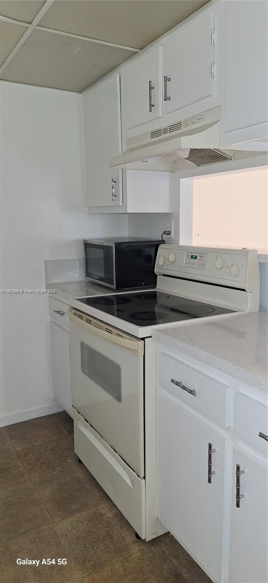 kitchen with electric stove and white cabinets