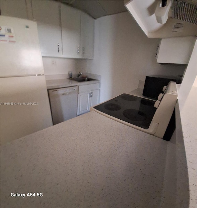 kitchen featuring white appliances, extractor fan, and white cabinets