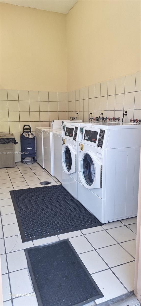 washroom with washing machine and dryer, tile walls, and light tile patterned floors