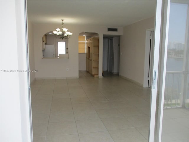 spare room featuring an inviting chandelier and light tile patterned floors