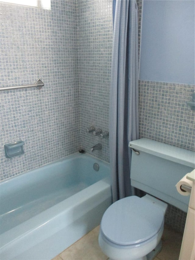 bathroom with shower / bath combination with curtain, tile walls, toilet, and tile patterned floors