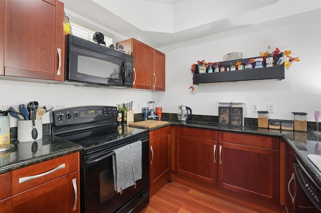 kitchen featuring dark stone counters, black appliances, and hardwood / wood-style floors