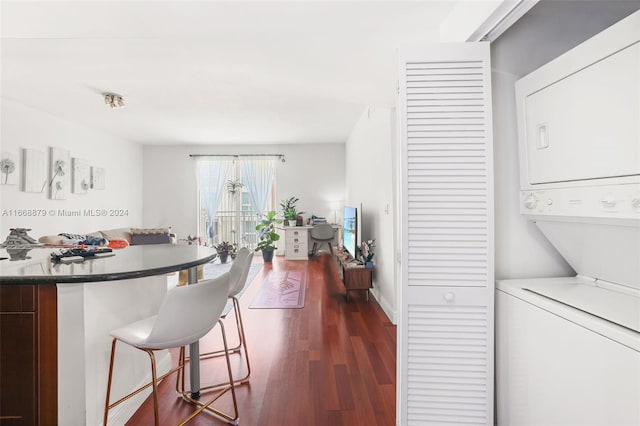 kitchen with a kitchen bar, stacked washer / dryer, and dark hardwood / wood-style floors