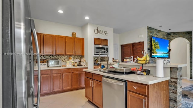 kitchen with sink, appliances with stainless steel finishes, light tile patterned floors, and tasteful backsplash