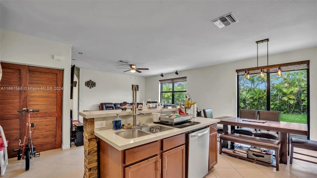 kitchen featuring dishwasher, ceiling fan, decorative light fixtures, a center island with sink, and sink