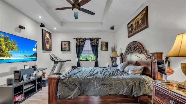 bedroom featuring ceiling fan, light hardwood / wood-style flooring, and a raised ceiling