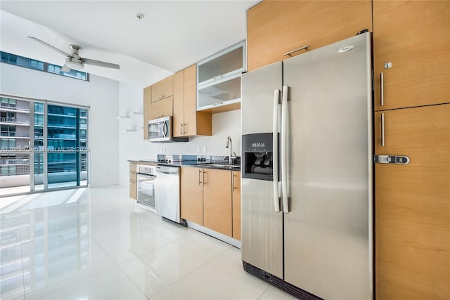 kitchen with a sink, dark countertops, appliances with stainless steel finishes, light tile patterned floors, and ceiling fan