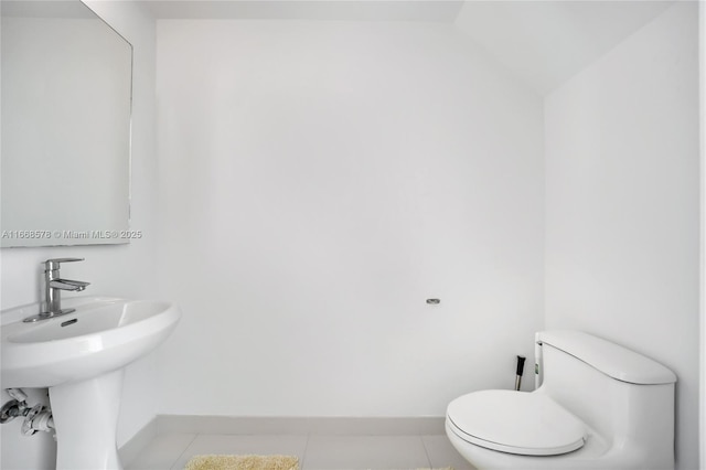 half bath featuring baseboards, lofted ceiling, a sink, tile patterned floors, and toilet