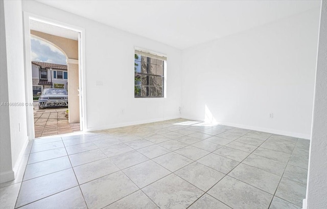 spare room with baseboards and light tile patterned flooring