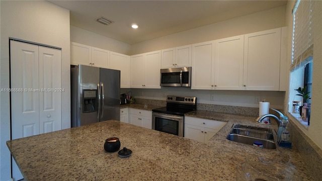 kitchen with white cabinetry, kitchen peninsula, appliances with stainless steel finishes, and sink