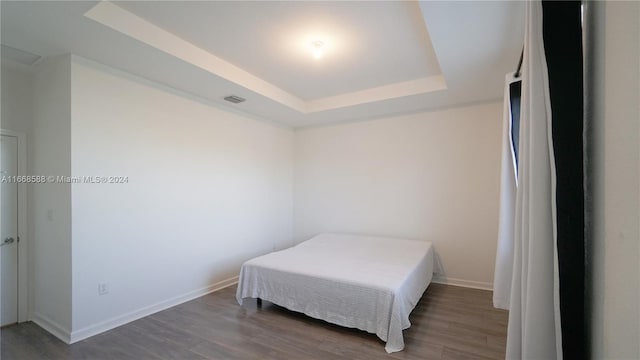 bedroom with a raised ceiling and dark hardwood / wood-style flooring