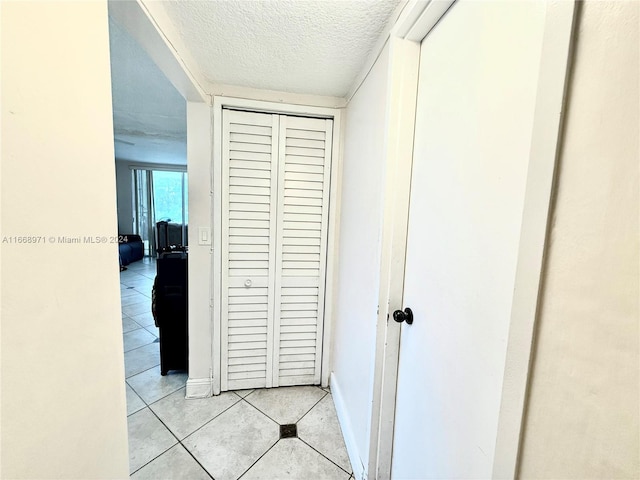 corridor featuring a textured ceiling and light tile patterned floors