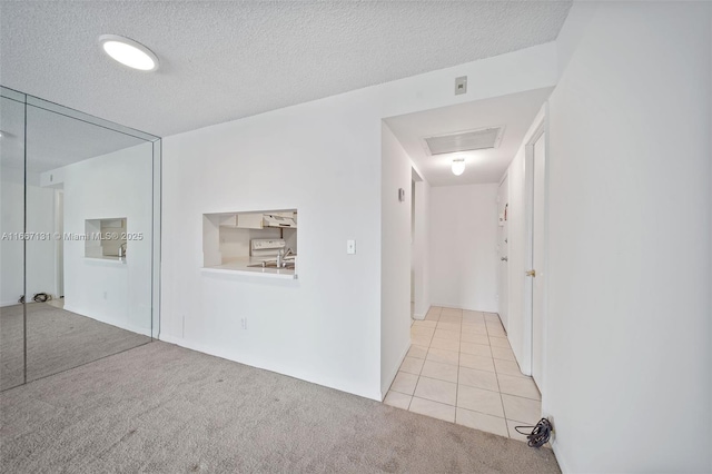 hallway featuring a textured ceiling and light carpet