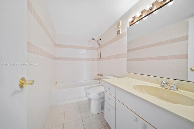 full bathroom with vanity, tiled shower / bath combo, tile walls, tile patterned flooring, and toilet