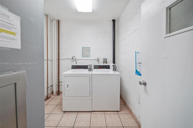 clothes washing area featuring washer and dryer and light tile patterned flooring