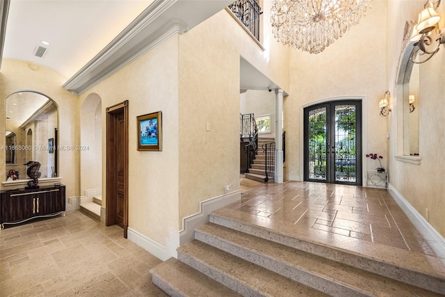 entrance foyer with french doors, an inviting chandelier, and a towering ceiling