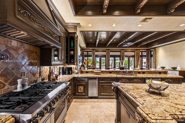 kitchen with light stone counters, premium range hood, beam ceiling, dark brown cabinets, and high end stove